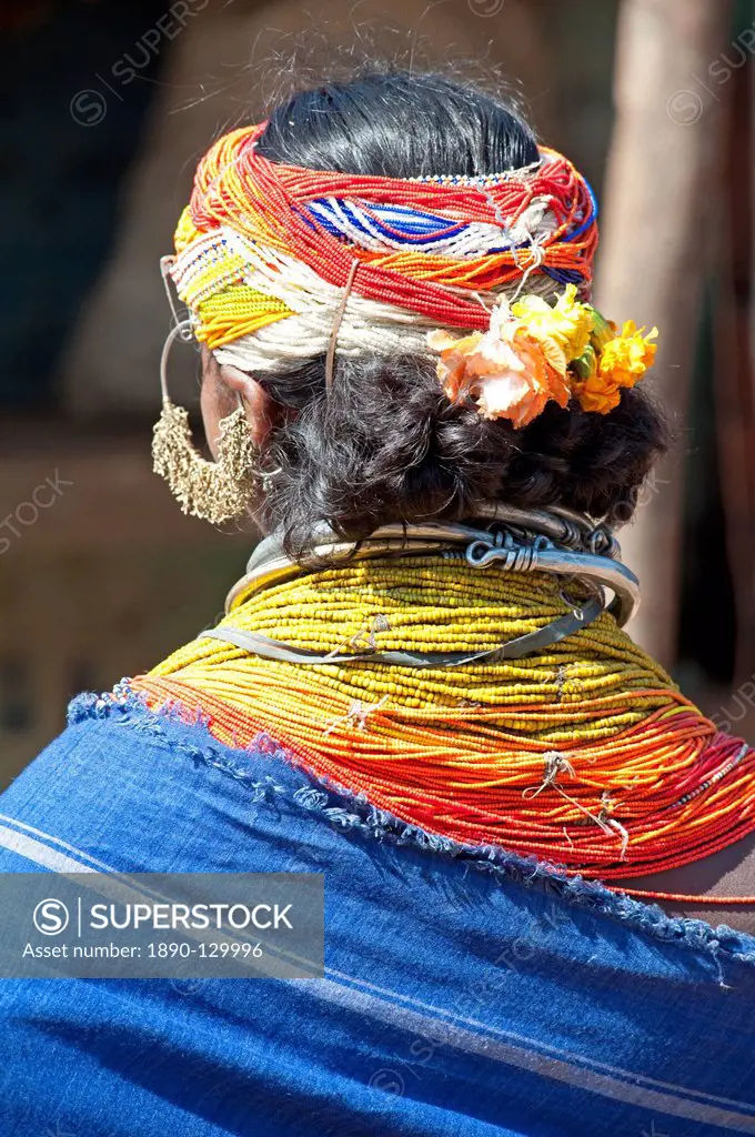 Bonda tribeswoman wearing blue cotton shawl over traditional bead costume, with beaded cap, large earrings and metal necklaces, Rayagader, Orissa, Ind...