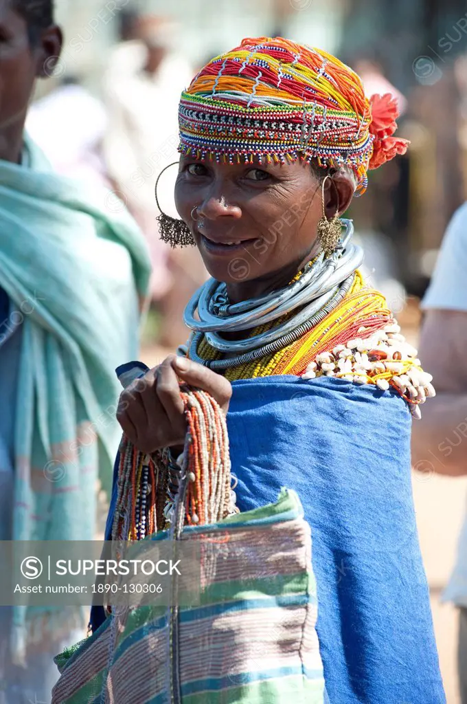 Smiling Bonda tribeswoman wearing cotton shawl over traditional bead costume, beaded cap, large earrings and metal necklaces, Rayagader, Orissa, India...