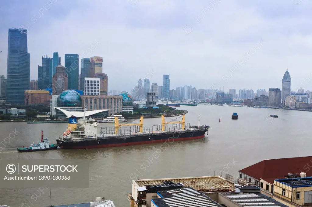 Large transport ship and tug on the Huangpu River that runs through Shanghai, China, Asia