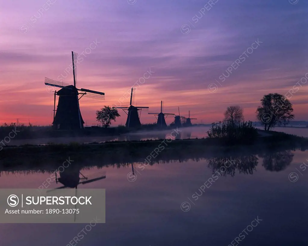 Reflections of a line of windmills in a misty landscape at Kinderdjik, UNESCO World Heritage Site, Holland, Europe