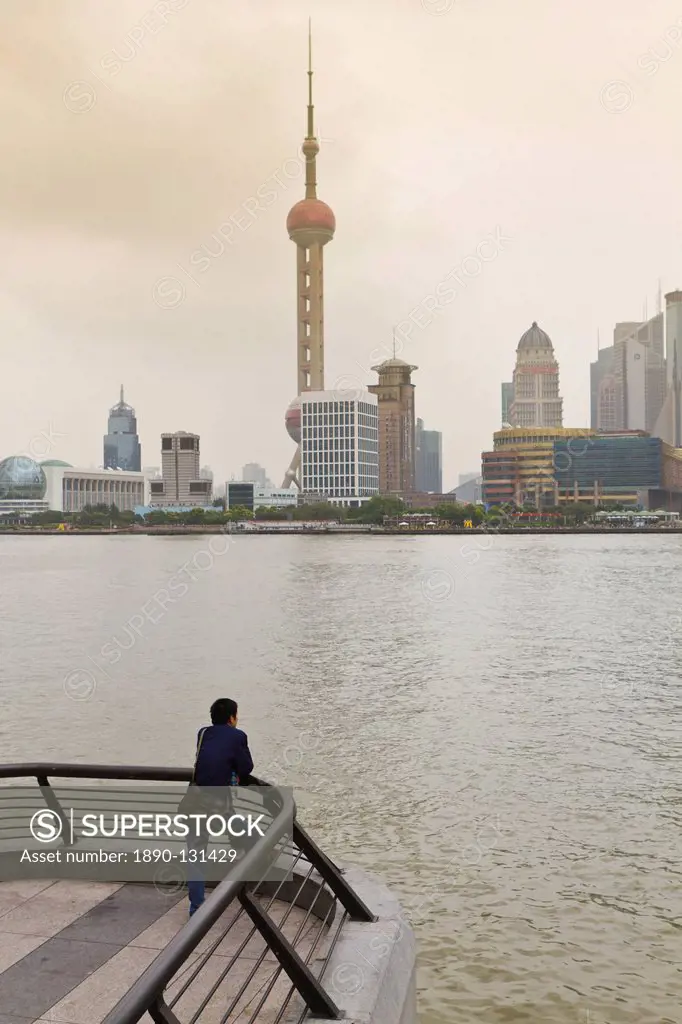 A man looking at the Oriental Pearl Tower and Pudong skyline across the Huangpu River from the Bund, Shanghai, China, Asia