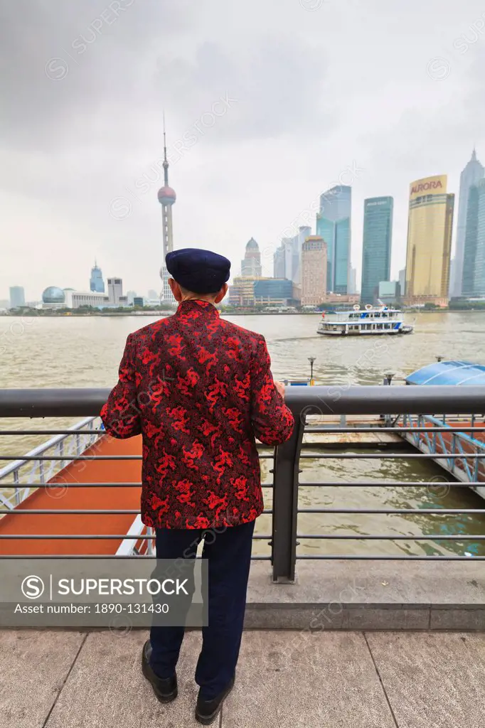 A man looking at the Pudong skyline from the Bund across the Huangpu River, Shanghai, China, Asia