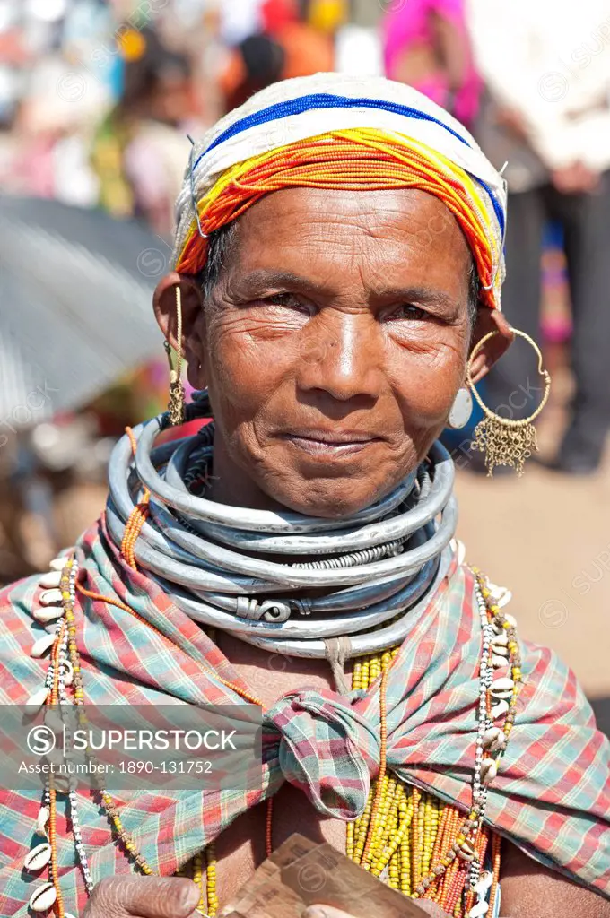 Smiling Bonda tribeswoman wearing cotton shawl over traditional bead costume, beaded cap, large earrings and metal necklaces, Rayagader, Orissa, India...