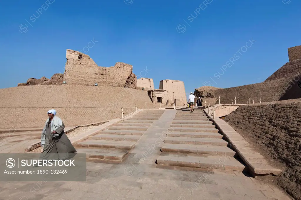 Man in jellabiya walking out of the Temple of Horus, Edfu, Egypt, North Africa, Africa