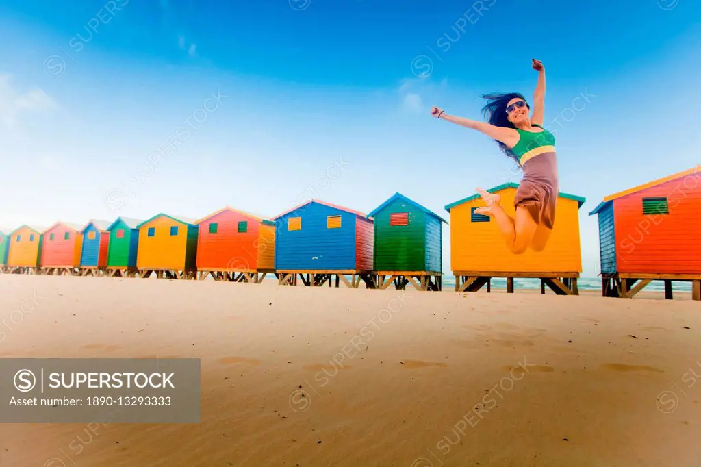 Laura Grier jumping in front of colorful beach huts, Muizenberg Beach, Cape Town, South Africa, Africa