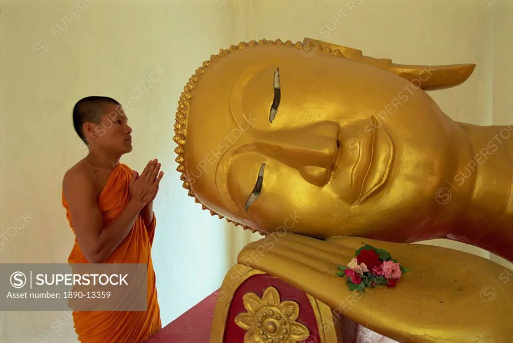 Novice monk and reclining Buddha, Wat Pha Baat Tai, Luang Prabang, Laos, Indochina, Southeast Asia, Asia