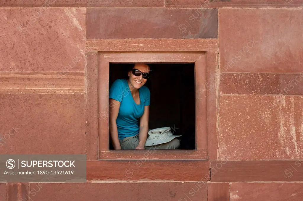 A tourist peeks out from one the windows within the Fatehpur Sikri temple complex, Uttar Pradesh, India, Asia