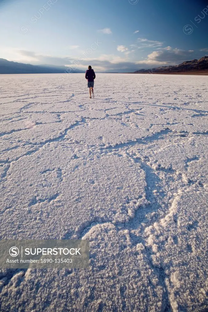 Woman walking on salt flats, Badwater Basin, at minus 282 feet the lowest point in the United States, Death Valley National Park, California, United S...
