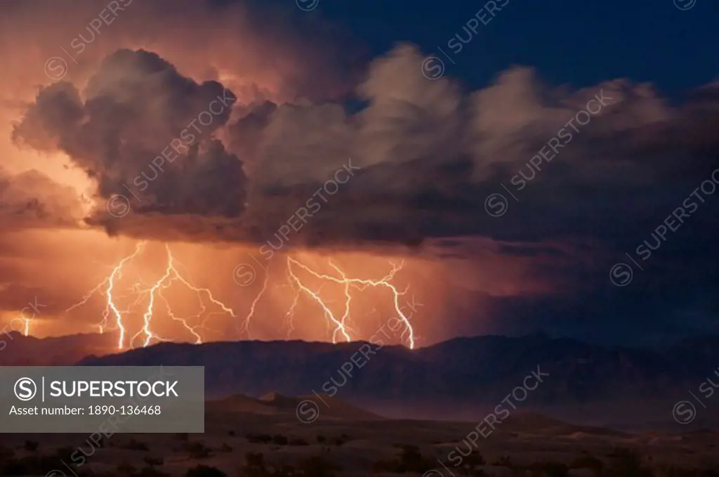 Electrical storm with forked lightning over the Grapevine mountains of the Amargosa Range, Mesquite Flats Sand dunes in the valley, Stovepipe Wells, Death Valley National Park, California, United States of America, North America