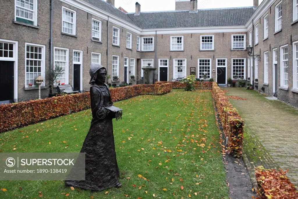 A statue of a nun stands in a courtyard of historic housing for women at the Begijnhof Beguinage, Breda, Noord_Brabant, Netherlands, Europe
