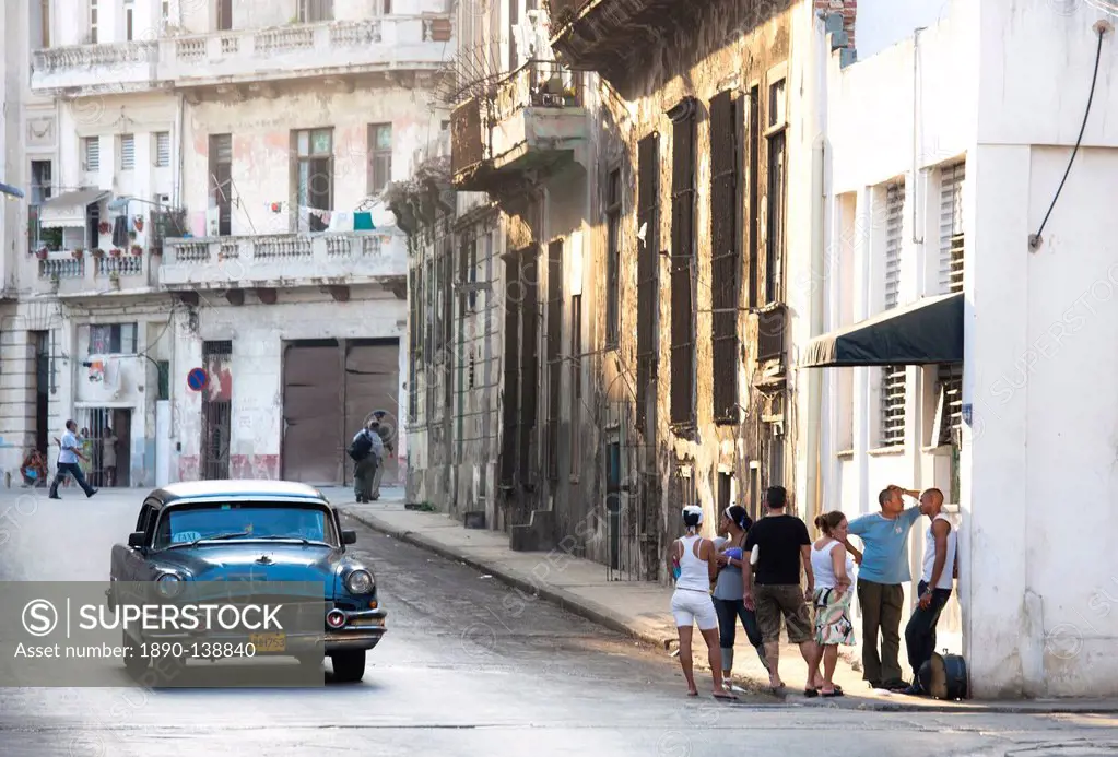 Street scene showing old American car operating as taxi for local people and a queue of people outside a shop, Havana, Cuba, West Indies, Central Amer...