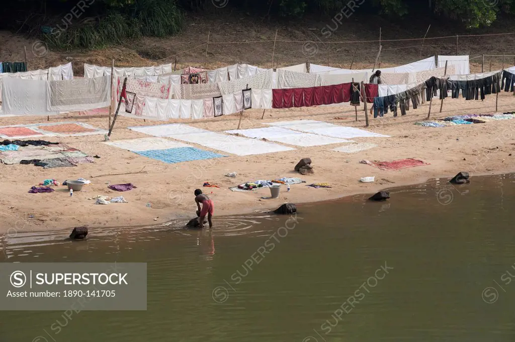 Dhobi wallah washing laundry in the river with neatly arranged washing drying on the sandy riverbank, Raghurajpur, Orissa, India, Asia