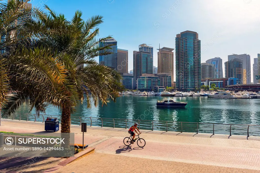 A lone cyclist rides along the waterfront, Dubai Marina, Dubai, United Arab Emirates, Middle East