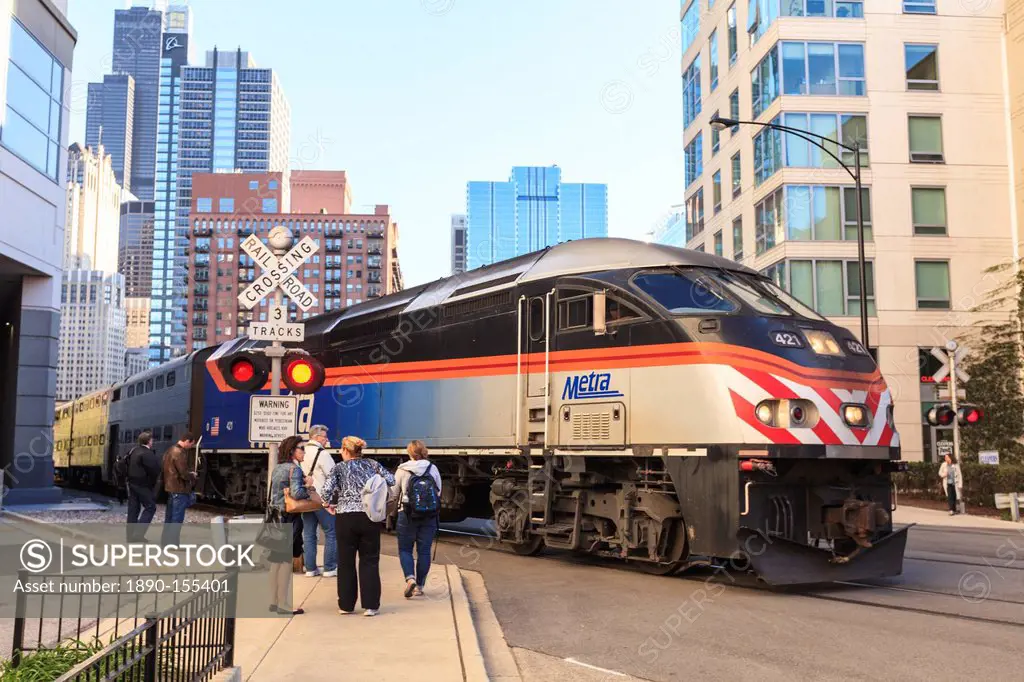 Metra Train passing pedestrians at an open railroad crossing, Downtown, Chicago, Illinois, United States of America, North America