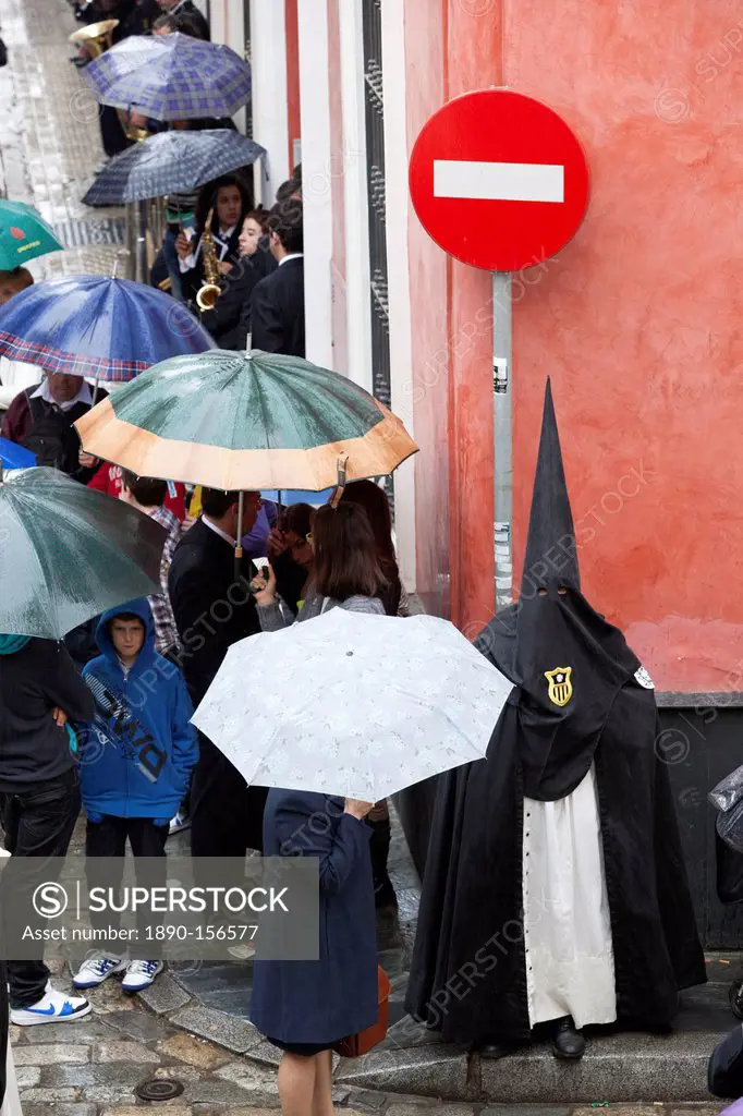 Penitent during Semana Santa (Holy Week) along rainy street, Seville, Andalucia, Spain, Europe