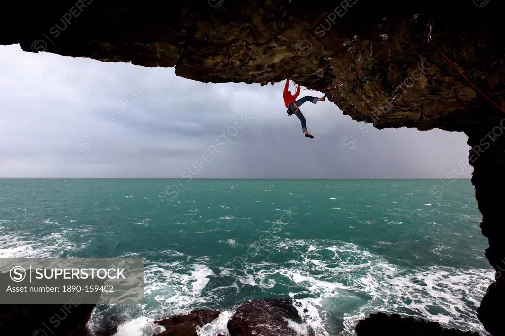 A climber scales cliffs near Swanage, Dorset, England, United Kingdom, Europe