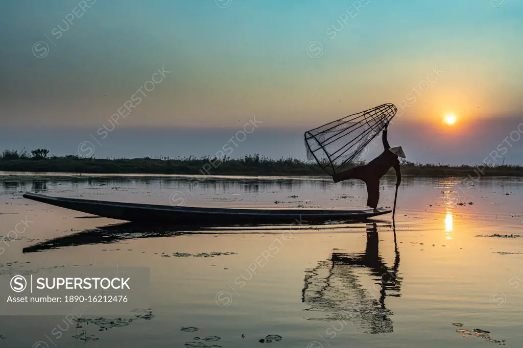 Fisherman at Inle Lake with traditional Intha conical net at sunset, fishing net, leg rowing style, Intha people, Inle Lake, Shan state, Myanmar (Burma), Asia