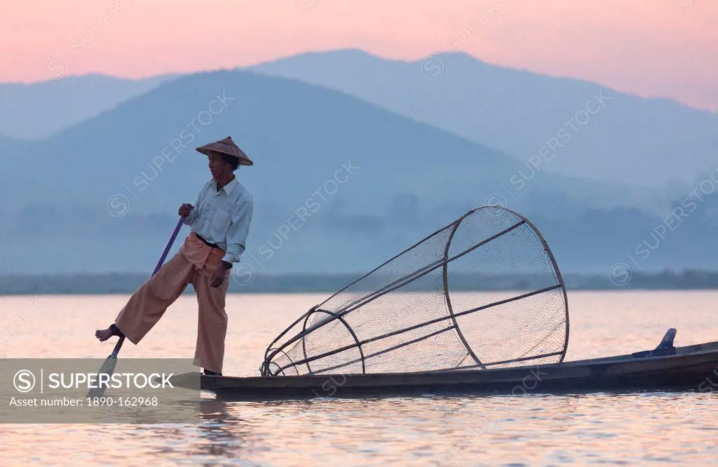 Intha 'leg rowing' fishermen at dawn on Inle Lake who row traditional wooden boats using their leg and fish using nets stretched over conical bamboo f...
