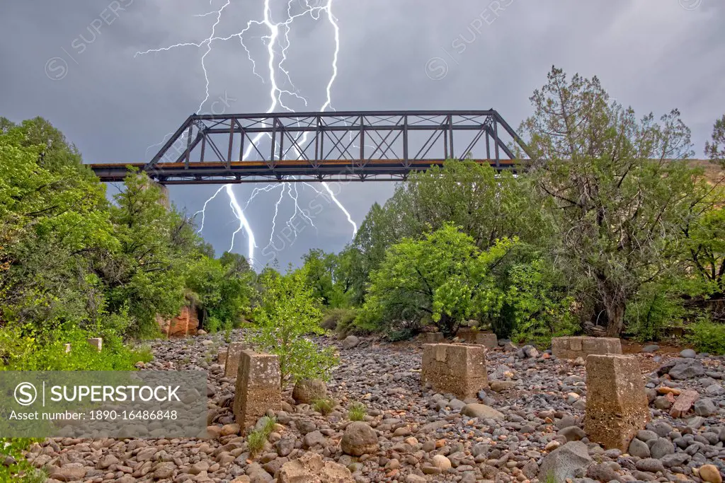Lightning from a monsoon storm striking behind an old railroad trestle bridge that spans Bear Canyon near Perkinsville, Arizona, United States of America, North America