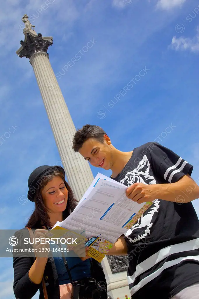 Young couple looking at map with Nelson's Column behind, Trafalgar Square, London, England, United Kingdom, Europe