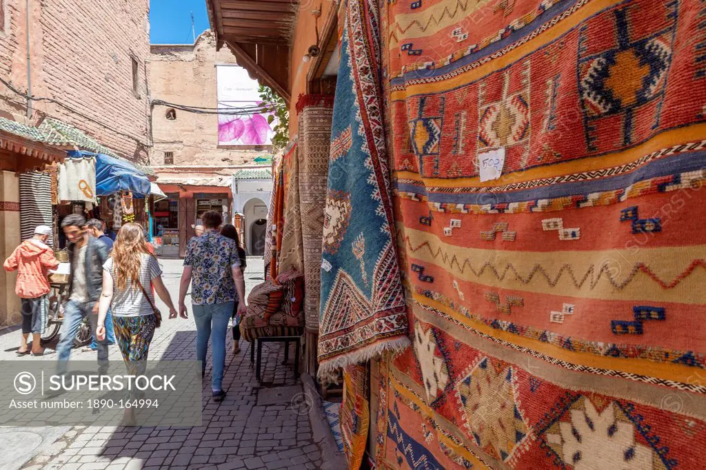 Tourists and locals walking alongside traditional rugs in the Medina's souks, Marrakech, Morocco, North Africa, Africa
