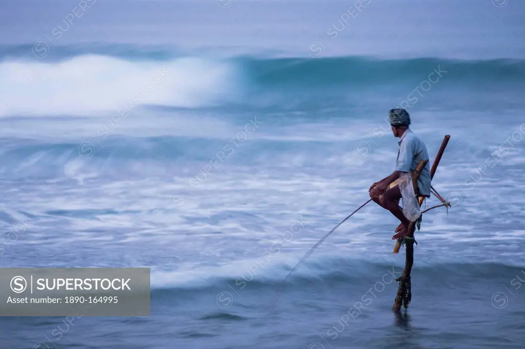 Stilt fishing, a stilt fisherman in the waves at Midigama near Weligama, South Coast, Sri Lanka, Indian Ocean, Asia
