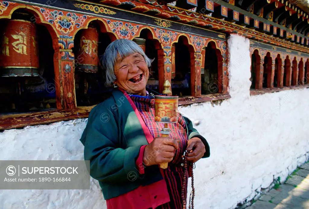 An old woman with prayer wheels laughing at the Kyichu Buddhist Temple in Paro, Bhutan