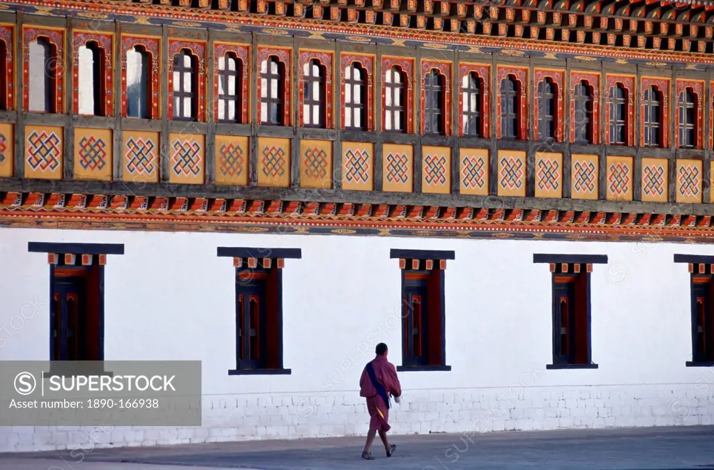 A man walking next to the Tashichho Dzong, home of the Government, Royal Palace and Religious Centre, in Thimpu, Bhutan