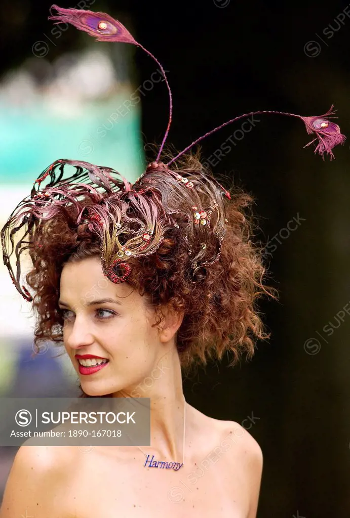 Race-goer wearing a hat which blends in with her hair at Royal Ascot Races. Her necklace has the word 'harmony'