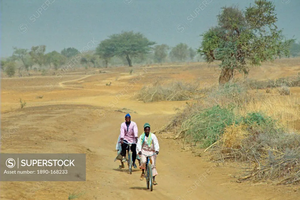 Two men cycling the deserted road to Sebba, Burkina Faso (formerly Upper Volta)