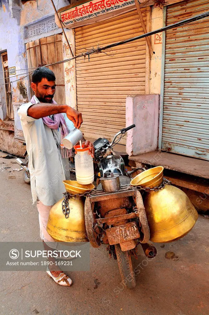 Milk collector carrying milk-churns on his motorbike, Pushkar, Rajasthan, India, Asia