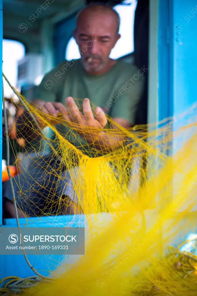 Fisherman cleaning his nets, Mykonos, Greek Islands, Greece, Europe