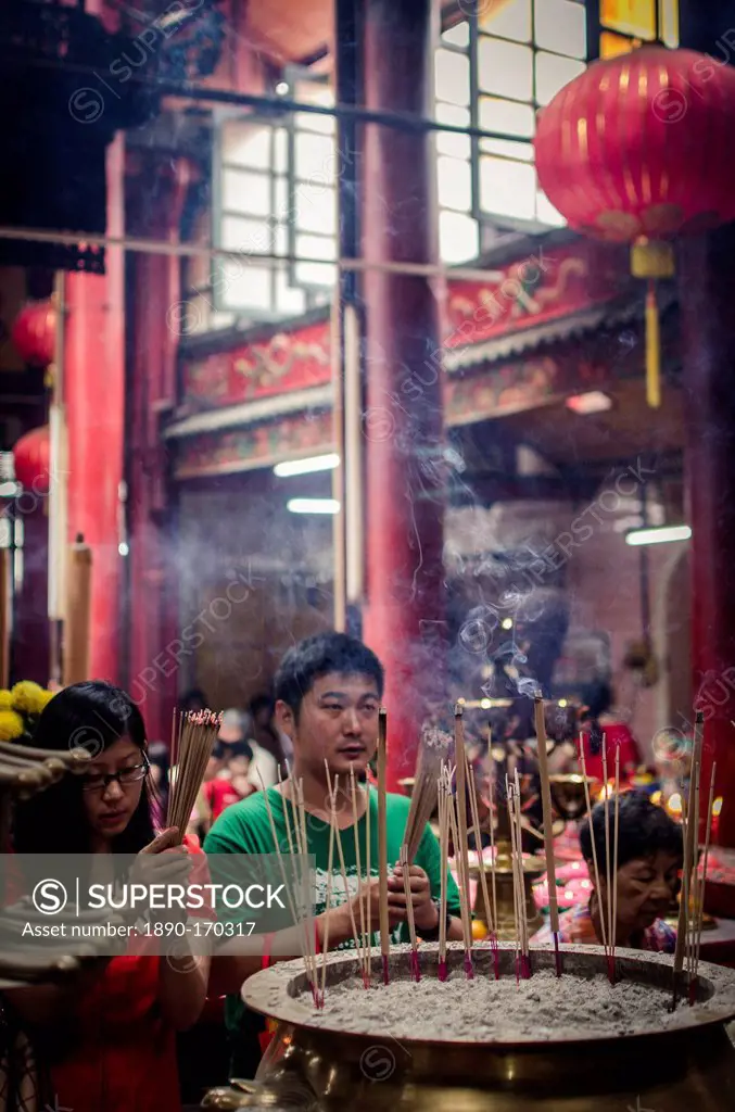 A man and women light incense sticks and pray during Chinese New Year celebrations, Sze Ya Temple, Chinatown, Kuala Lumpur, Malaysia, Southeast Asia, ...