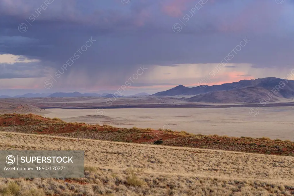 Some much needed rain falls in the distance at dusk in NamibRand Nature Reserve, Namib Desert, Namibia, Africa