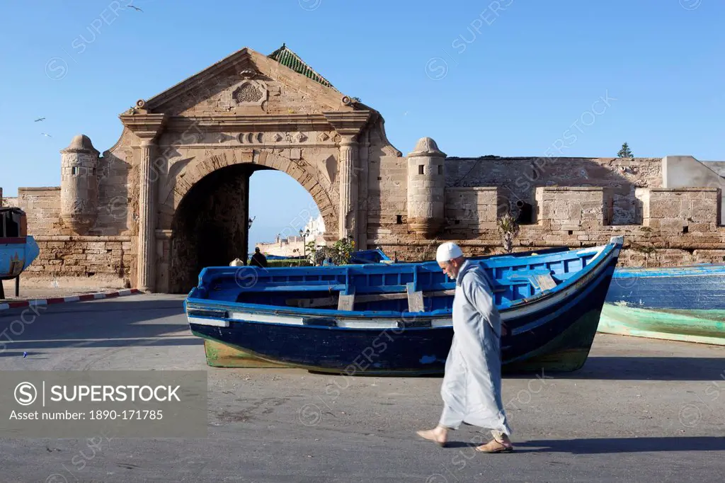 Old Muslim man walking below the old city gate and ramparts, Essaouira, Atlantic coast, Morocco, North Africa, Africa