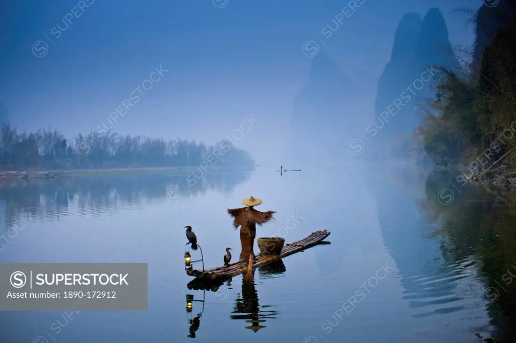 Fisherman in Suoyi coat and coolie hat fishes with cormorants on Li River near Guilin, China
