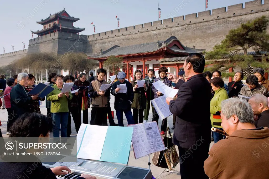 People gather to form an informal choir, part of the morning exercise in the park by the City Wall, Xian, China