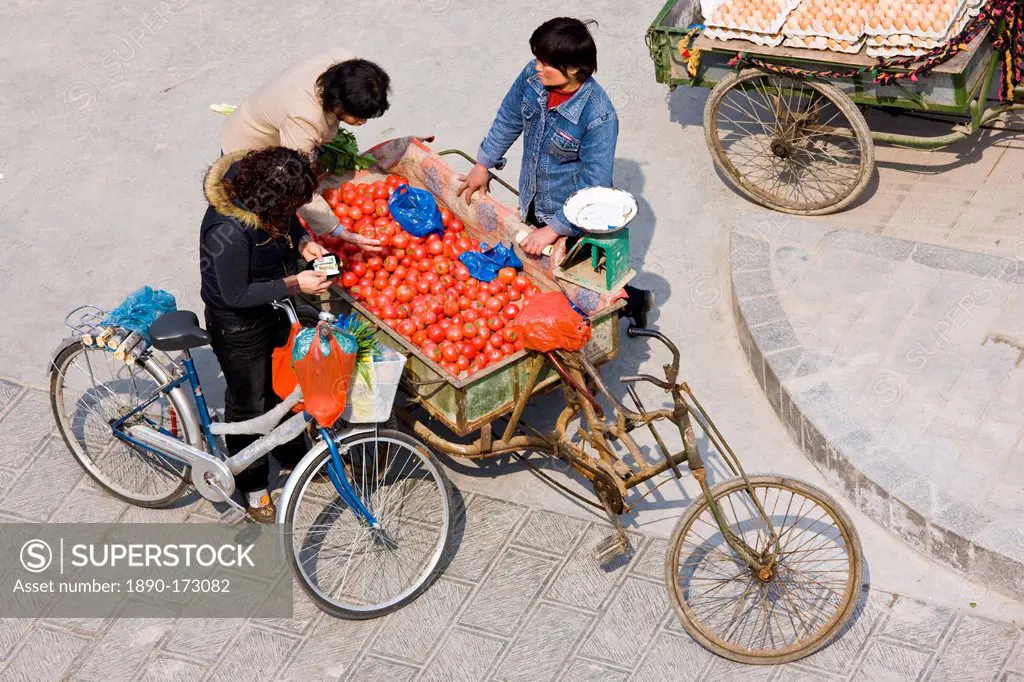 Women buying tomatoes from cart in street market, viewed from the City Wall, Xian, China