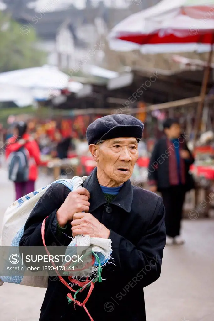 Elderly Chinese man carrying sack through Chongqing, China