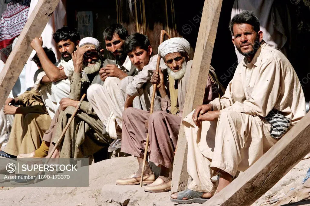 Pakistani men sit together in earthquake devastated village of Pattika, Pakistan