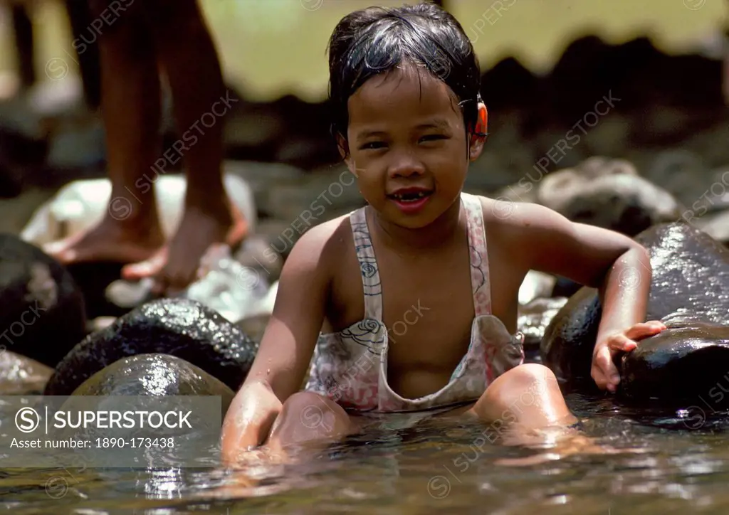 A young child washing in a river in the Philippines
