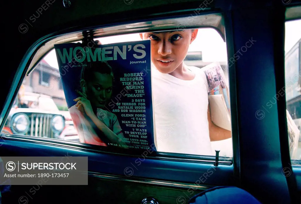 Boy sells magazines at car windows in Manila, Philippines