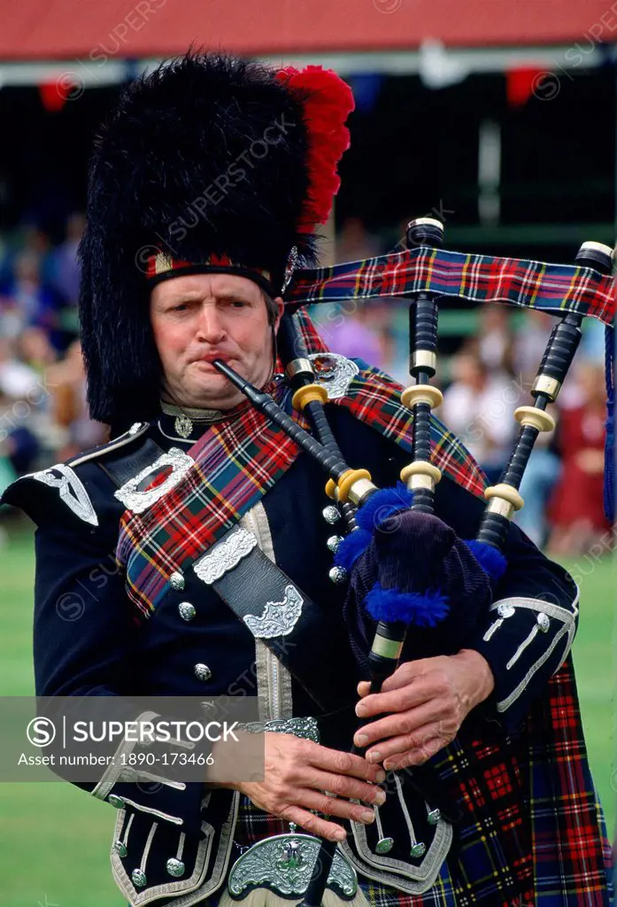 A Scotsman playing the Bagpipes at the Braemar Games, a Royal Highland gathering. He is wearing a traditional tartan costume and a busby style hat.