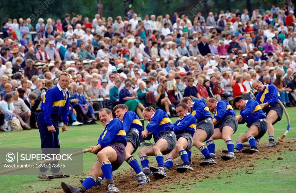 A huge crowd watching a team of men taking part in a tug-of-war competition at the Braemar Games, a Royal Highland gathering.