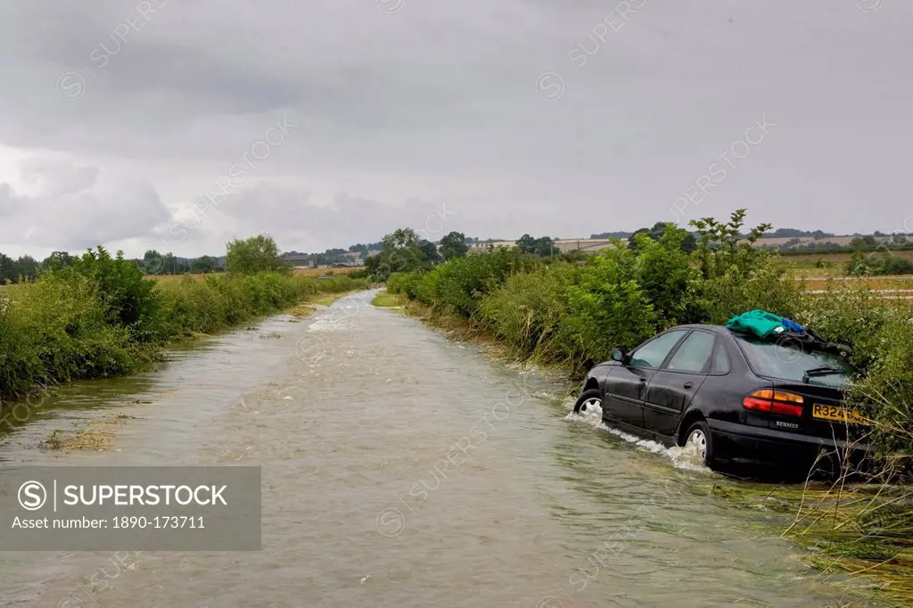 Car forced off the road by flood water sweeping from field to field in Lyneham, Oxfordshire, England, United Kingdom