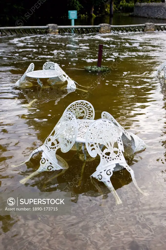 Outdoor tables and chairs of The Swan Hotel submerged in flood water, Minster Lovell, Oxfordshire, United Kingdom