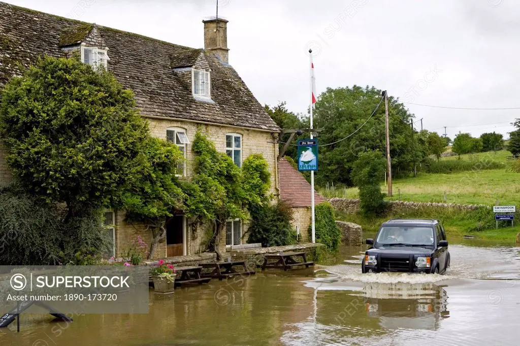 Four wheel drive car drives through flooded road in Swinbrook, Oxfordshire, England, United Kingdom