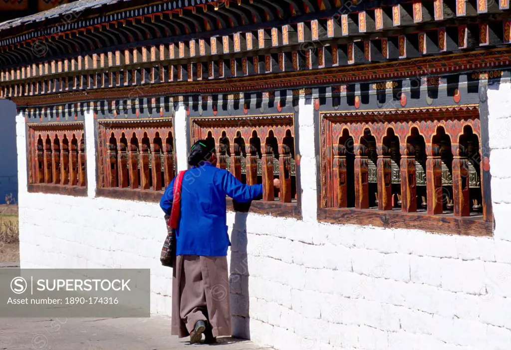 Bhutanese woman touching prayer bells while praying at the Tashichho Dzong in Bhutan