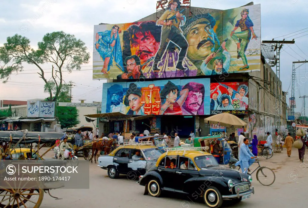 Street scene in Islamabad, Pakistan showing rickshaws, an old two-tone Morris Minor car and the local cinema advertising films often described as Boll...