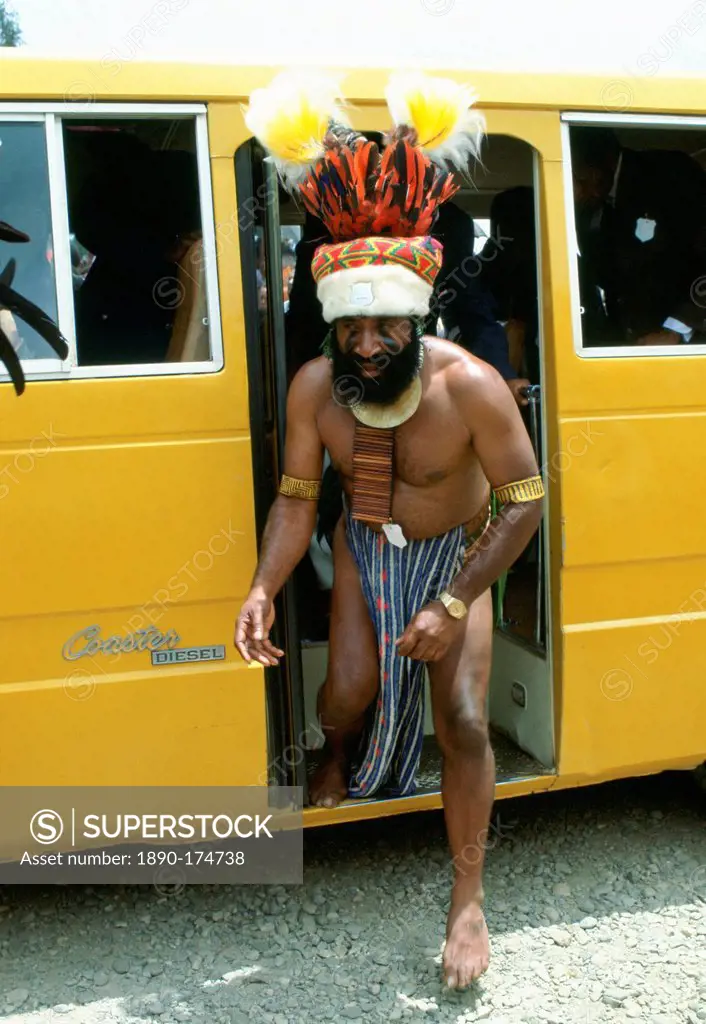 Bearded tribesman in feathered headdress steps from a modern minibus during a gathering of tribes at Mount Hagen in Papua New Guinea